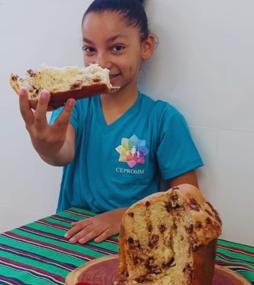 Crianca atendida pelo CEPROMM com o panetone produzido na Padaria Sabor do Bem Divulgacao